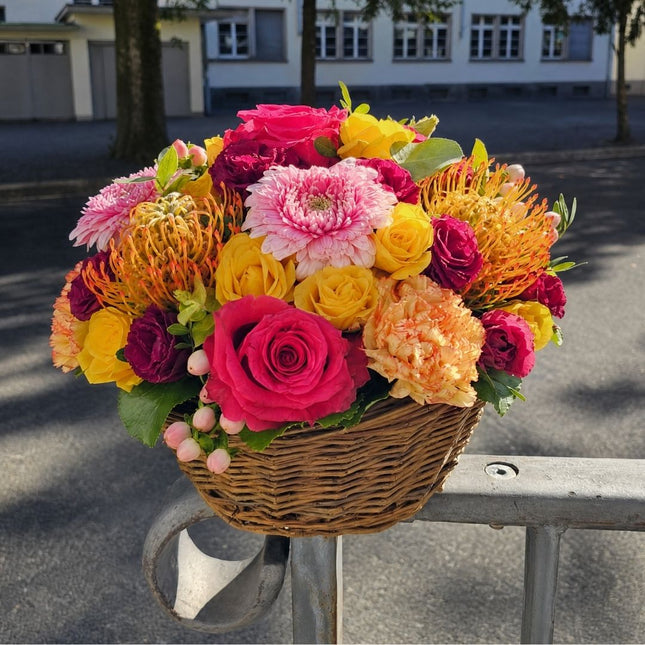 Farbenfroher Blumenkorb mit pinken und gelben Rosen, rosa Chrysanthemen, bordeauxfarbenen Blüten und saisonalen Blumen online bestellen Zürich