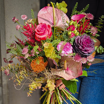 Farbenfroher Blumenstrauss mit pinken Rosen, rosa Anthurien, violettem Zierkohl, orangefarbener Protea und Eukalyptus von Blumen Krämer Zürich