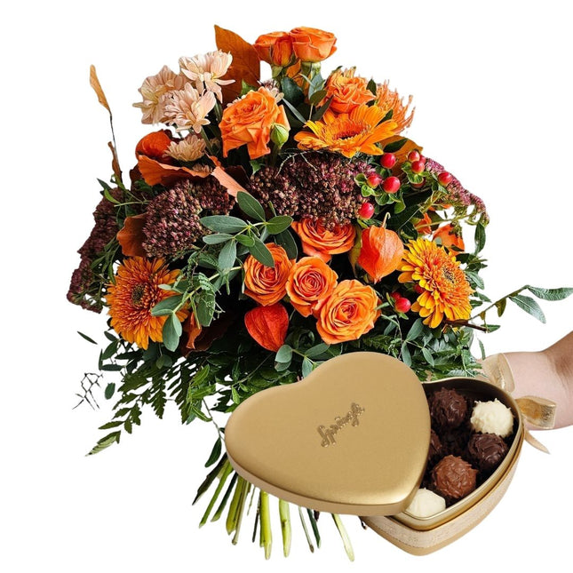 Leuchtender Herbststrauss in Orange mit Chrysanthemen, Rosen und Hagebutten mit Sprüngli Schokolade