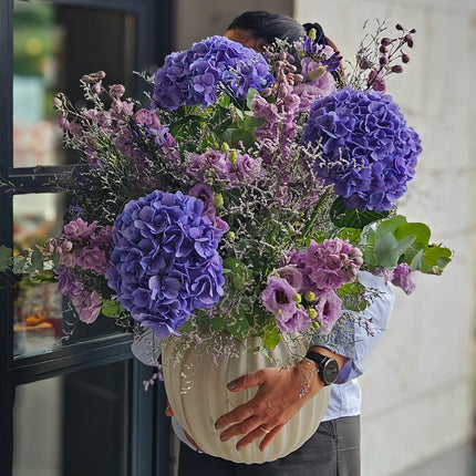 Lila Blumenstrauss mit violetten Hortensien, rosa Rittersporn, Lisianthus und Eukalyptus in Vase