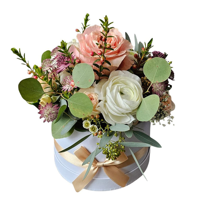Elegante Blumenbox mit Rosen, Ranunkeln und Eukalyptus in Rosé- und Cremetönen in runder Geschenkbox mit Schleife